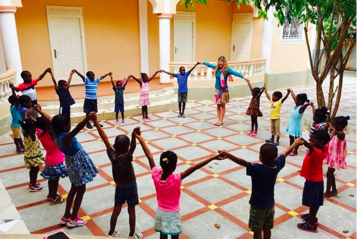 Lisa holding hands in a circle with children in Haiti